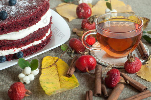 一杯茶和一个<strong>漂亮</strong>的自制蛋糕放在亚麻布表面，上面装饰着蓝莓、臀部、<strong>花边</strong>和肉桂枝