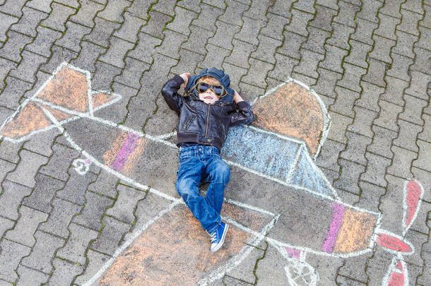 小男孩用粉笔画飞机图画玩得很开心