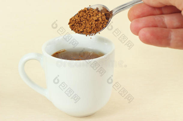 手从咖啡杯里的勺子里倒速溶咖啡