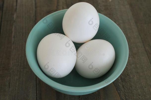 一碗新鲜的全鸡蛋在一个木制的背景上隔离