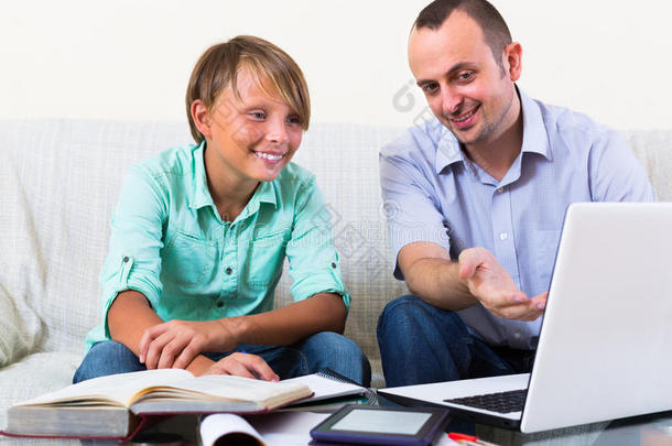 带笔记本电脑的成年男子和男孩在室内