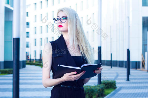 商务女士带着笔记本在商务中心的背景上看着远处