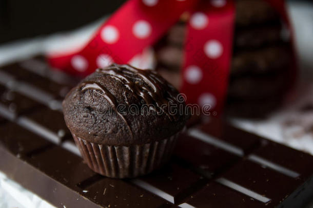 松饼和巧克力曲奇配巧克力棒和带白点的红色丝绸蝴蝶结