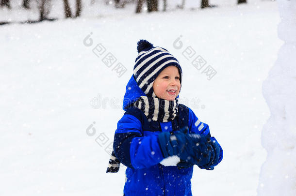 可爱的小男孩在冬天堆雪人