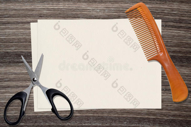 木头背景上的梳子、剪刀和纸