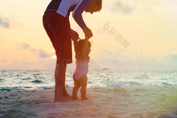 父亲和小女儿在日落海滩散步