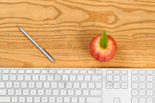 电脑键盘，桌面上有钢笔和苹果