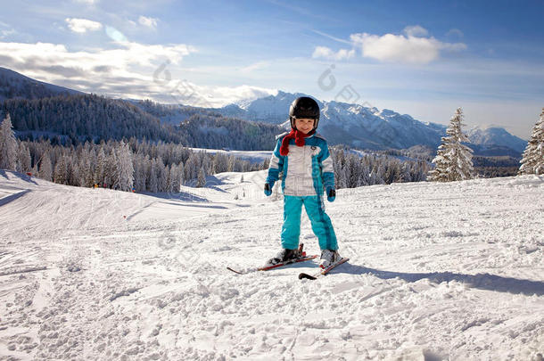 可爱的小男孩，穿着蓝色夹克和头盔，滑雪