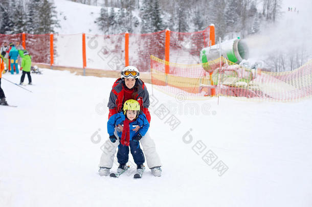 美丽的年轻妈妈和她蹒跚学步的男孩，在山上滑雪