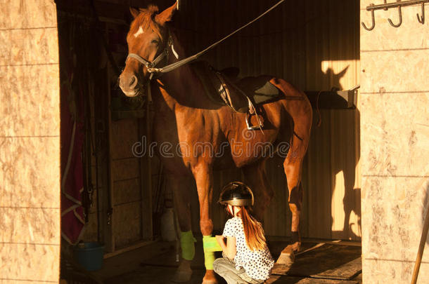 女孩把她的马装上马鞍，准备骑马