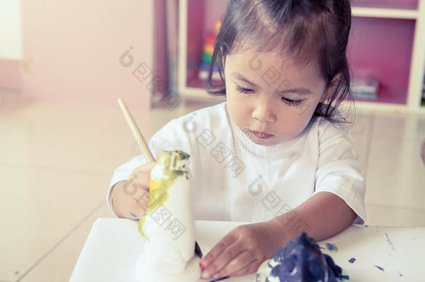 孩子画，小女孩玩得很开心，在灰泥娃娃上画画