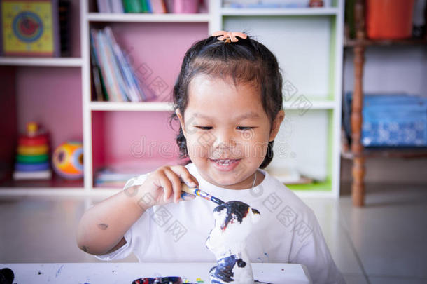 孩子画，小女孩玩得很开心，在灰泥娃娃上画画