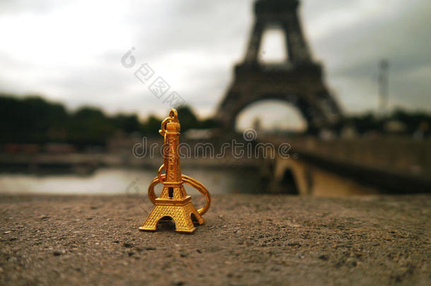 金色纪念品-一个微型埃菲尔铁塔在真实的东西前面