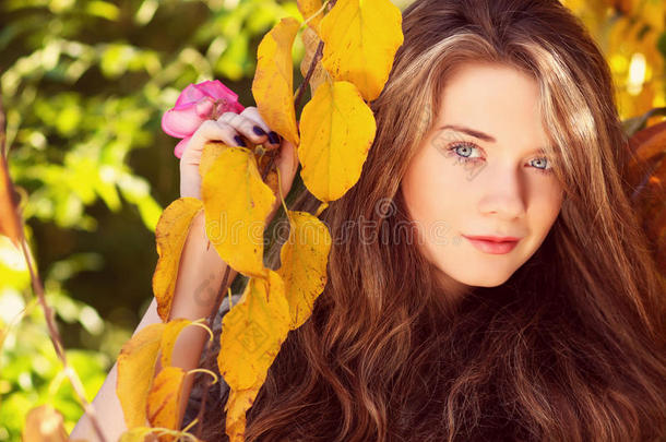 美丽的模特，秋天的叶子和秋天的黄色花园
