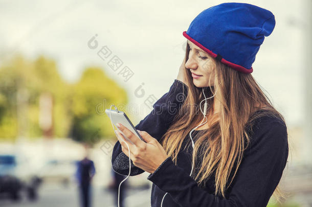 漂亮的女人模特在街上带着电话和耳机