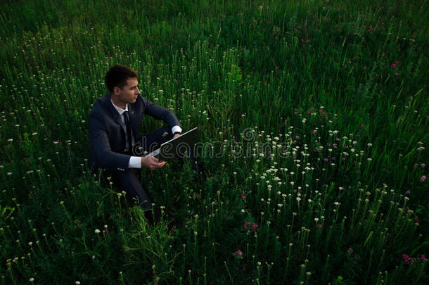 带着笔记本电脑的布尼斯曼坐在草地上