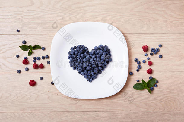 美丽多汁的成熟天然有机覆盆子，黑莓，蓝莓和薄荷蓝色桌布点白色<strong>菜心</strong>形状