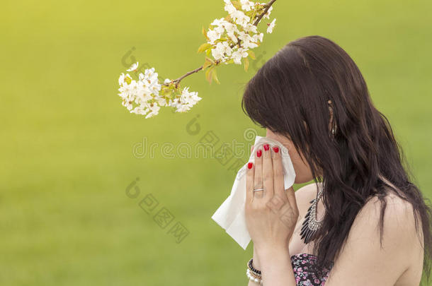 美丽的干草女孩在春天的大自然中擦拭她的鼻子