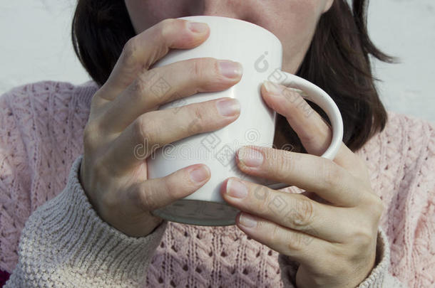 一个女人在近旁的杯子里喝茶。