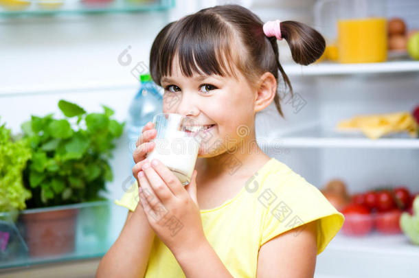 女孩喝牛奶站在冰箱附近