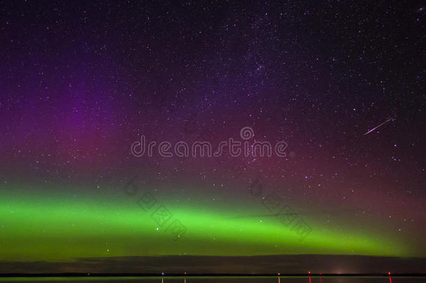 绿色，洋红和紫色北极光与流星在北达科他州的一个湖泊上