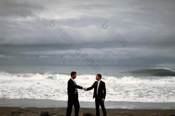 商人握手海滩合作协议的概念