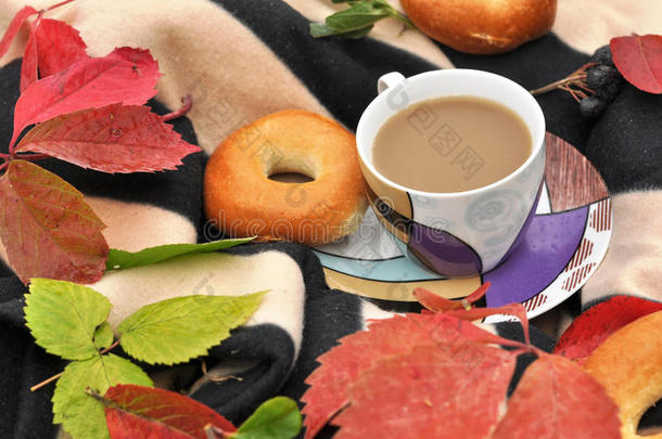 <strong>一杯奶</strong>茶，甜蜜的新鲜面包和五颜六色的秋叶在条纹温暖的野餐毯上
