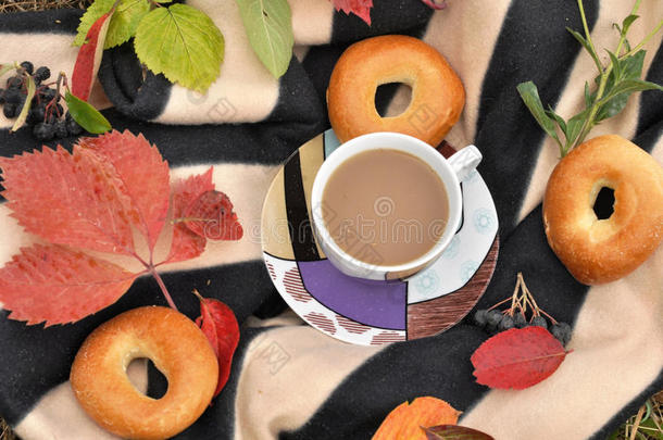 <strong>一杯奶</strong>茶，甜蜜的新鲜面包和五颜六色的秋叶在条纹温暖的野餐毯上