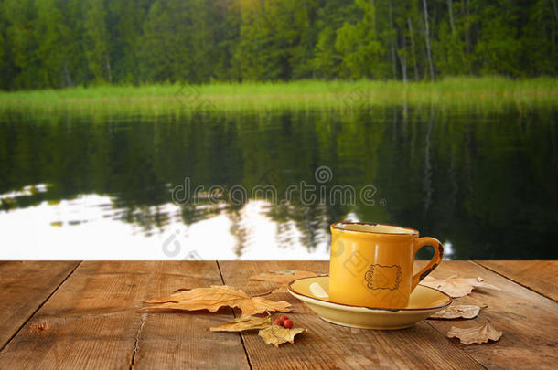 咖啡杯的正<strong>面形</strong>象在木桌上，在湖和森林背景前<strong>面</strong>