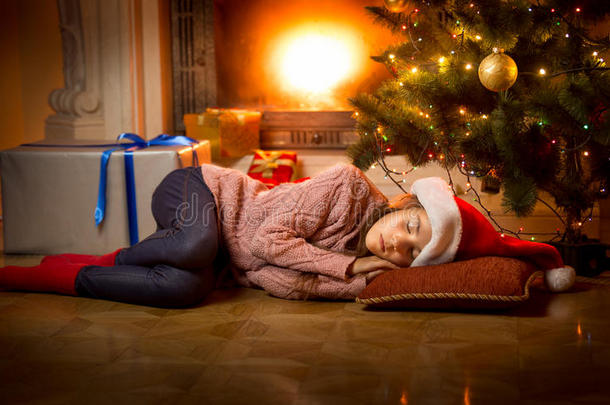 女孩睡在壁炉旁边的圣诞树<strong>下</strong>的地板上