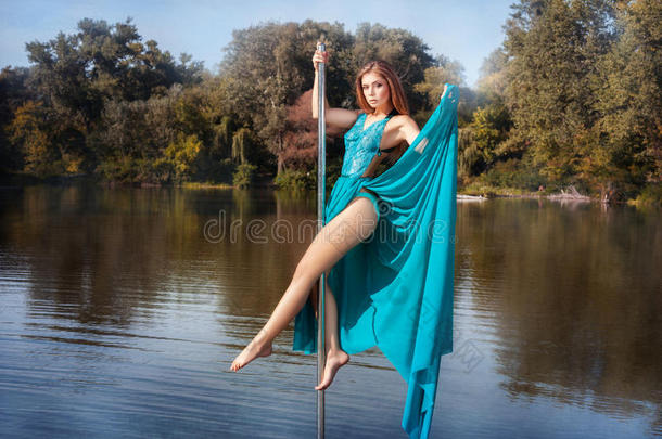 女孩穿裙子在湖里的杆子上跳舞。