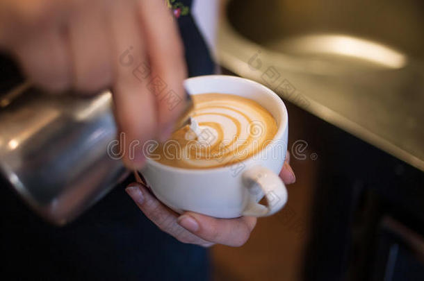 咖啡师制作拿铁艺术，专注于牛奶和咖啡