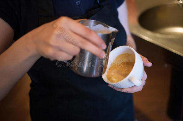 咖啡师制作拿铁艺术，专注于牛奶和咖啡