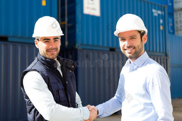 码头工人和主管在集装箱前握手