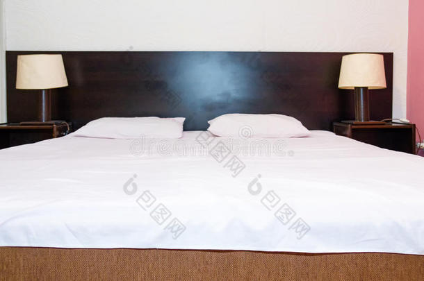 床上有白色床单和枕头，上面有两盏床头灯