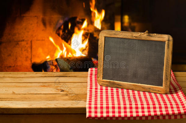 壁炉背景上木制桌子上的黑板。 寒假和圣诞节假期