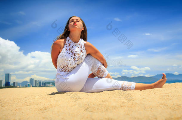 女孩在海滩上的花边在瑜伽体式交错的手臂后面