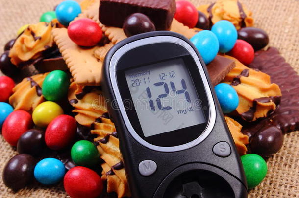 血糖仪和一堆糖果在黄麻煎饼，糖尿病和不健康的食物