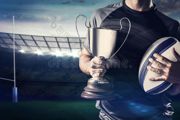 成功橄榄球运动员手持奖杯和球的中段的复合图像
