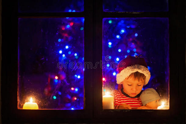 可爱的小男孩，晚上坐在窗户上，看着户外，