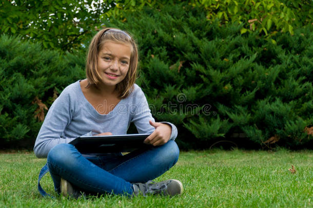 女孩在花园里学习平板电脑，快乐地微笑