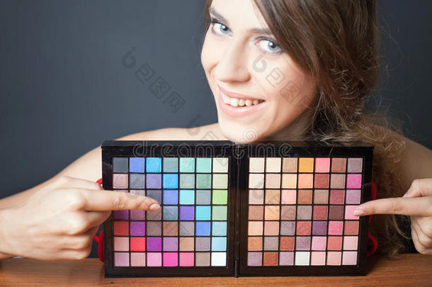 迷人的女人指着五颜六色的调色板进行时尚化妆