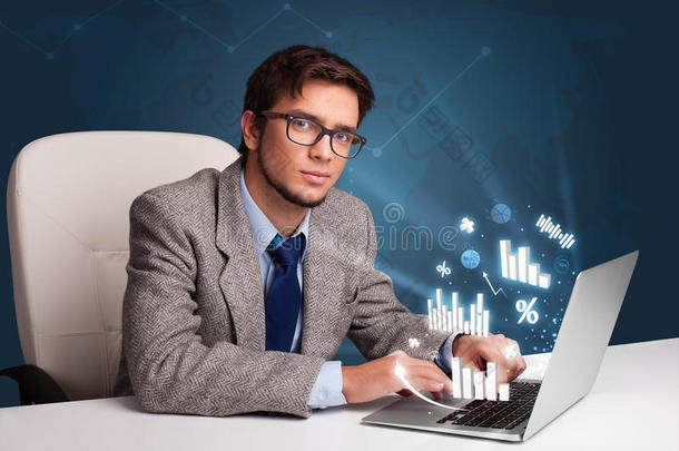 年轻人坐在办公桌旁，用<strong>笔记本</strong>电脑打字，<strong>上面</strong>有图表和
