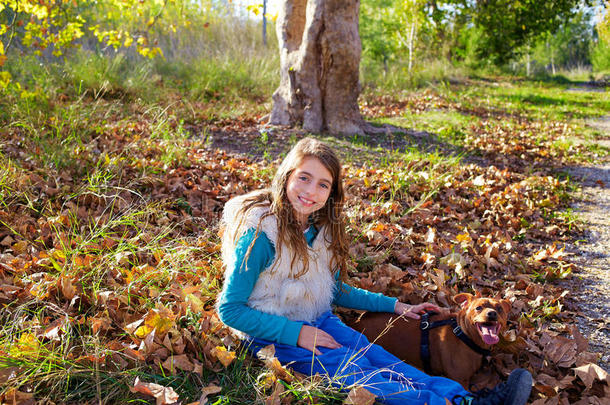秋天的小女孩带着宠物狗在秋天的森林里放松