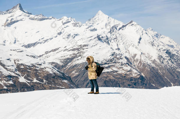 一名男子在雪山背景雪地上用老式<strong>胶卷相机</strong>拍照。