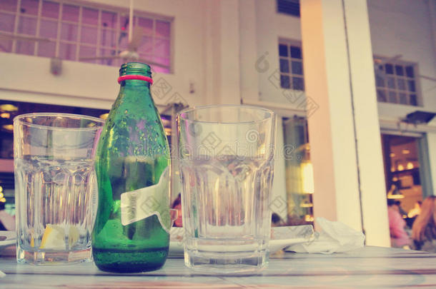 晚上露天咖啡馆桌子上的瓶子和眼镜；复古的生活方式概念