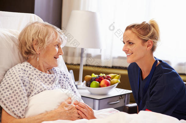 护士在<strong>病床</strong>上与高龄女病人交谈