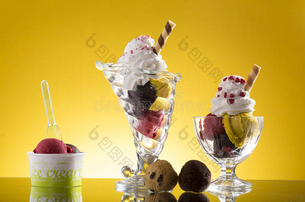 黄色背景上五颜六色的冰淇淋杯和塑料杯
