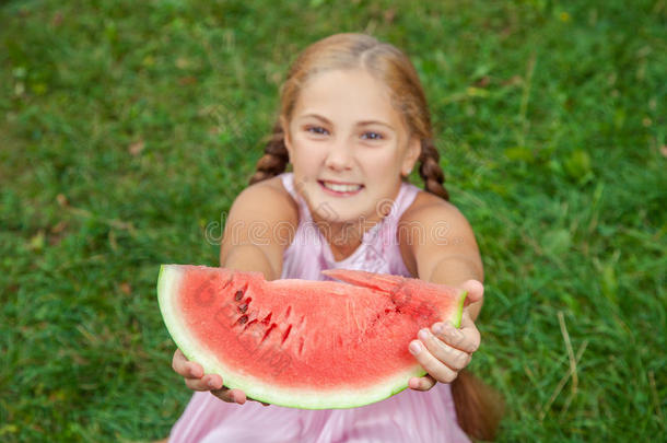 夏天可爱的<strong>小女孩</strong>在<strong>草地上</strong>吃西瓜。 马尾辫，长发，牙齿微笑，坐在<strong>草地上</strong>，享受着乐趣