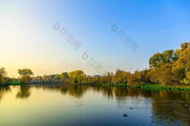 日落时，城市公园里有树木和湖泊的秋天景观